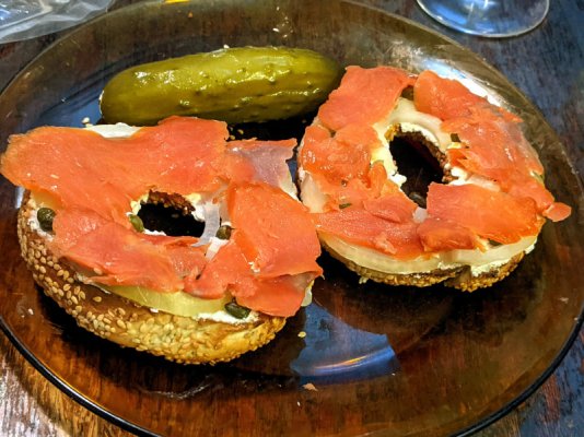 Smoked salmon on a bagel with quark, onion, and capers with a pickle on the side.jpg