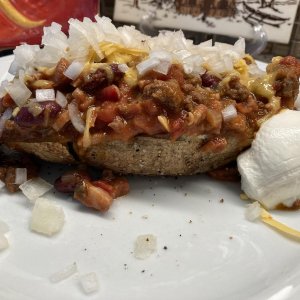 Baked Potato smothered in my homemade Paniolo Chili, topped with chopped sweet White Onions, shredded Cheddar Cheese and a dollop of "Daisy" on the si